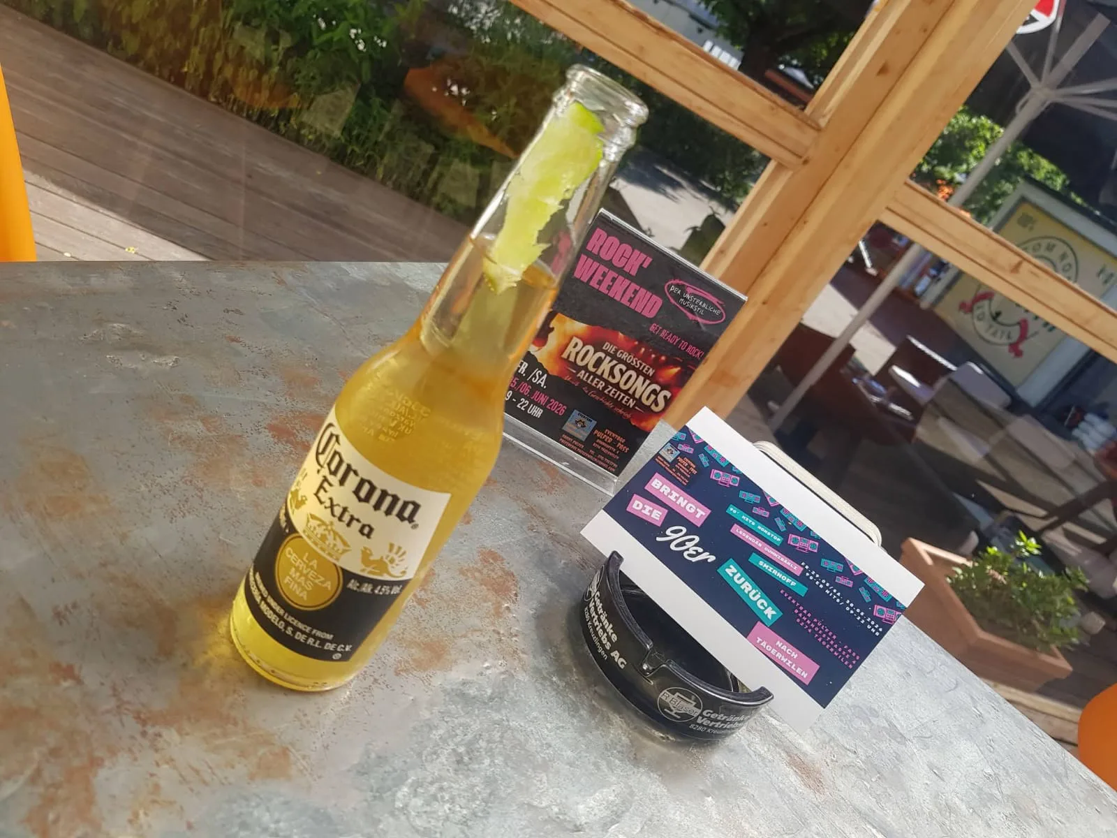 Eine Flasche Corona Extra auf einem Tisch, daneben liegen Flyer des Betriebs.