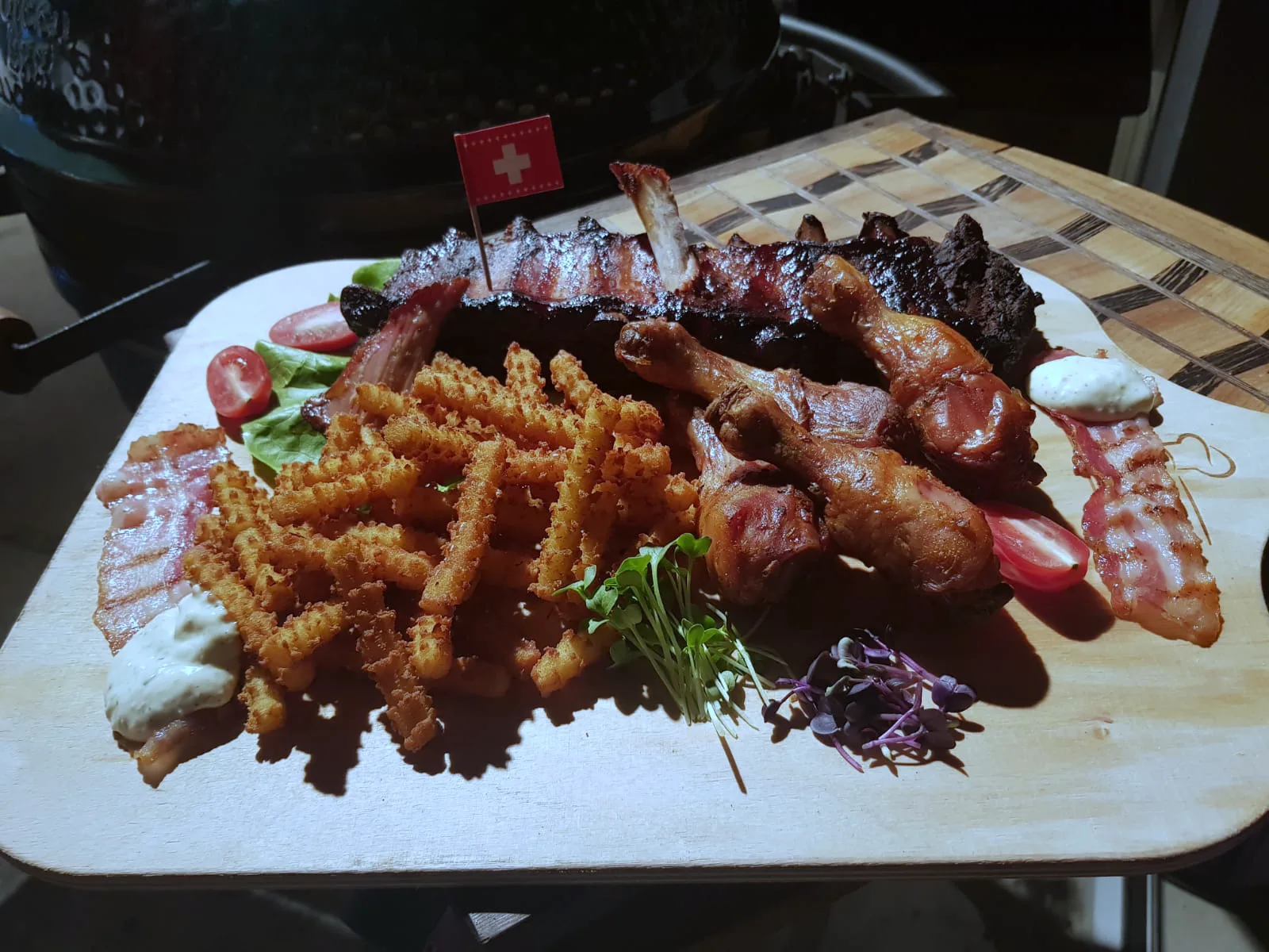 Ein Holzbrett mit Würsten vom Grill, Crispy Fries und Salat.